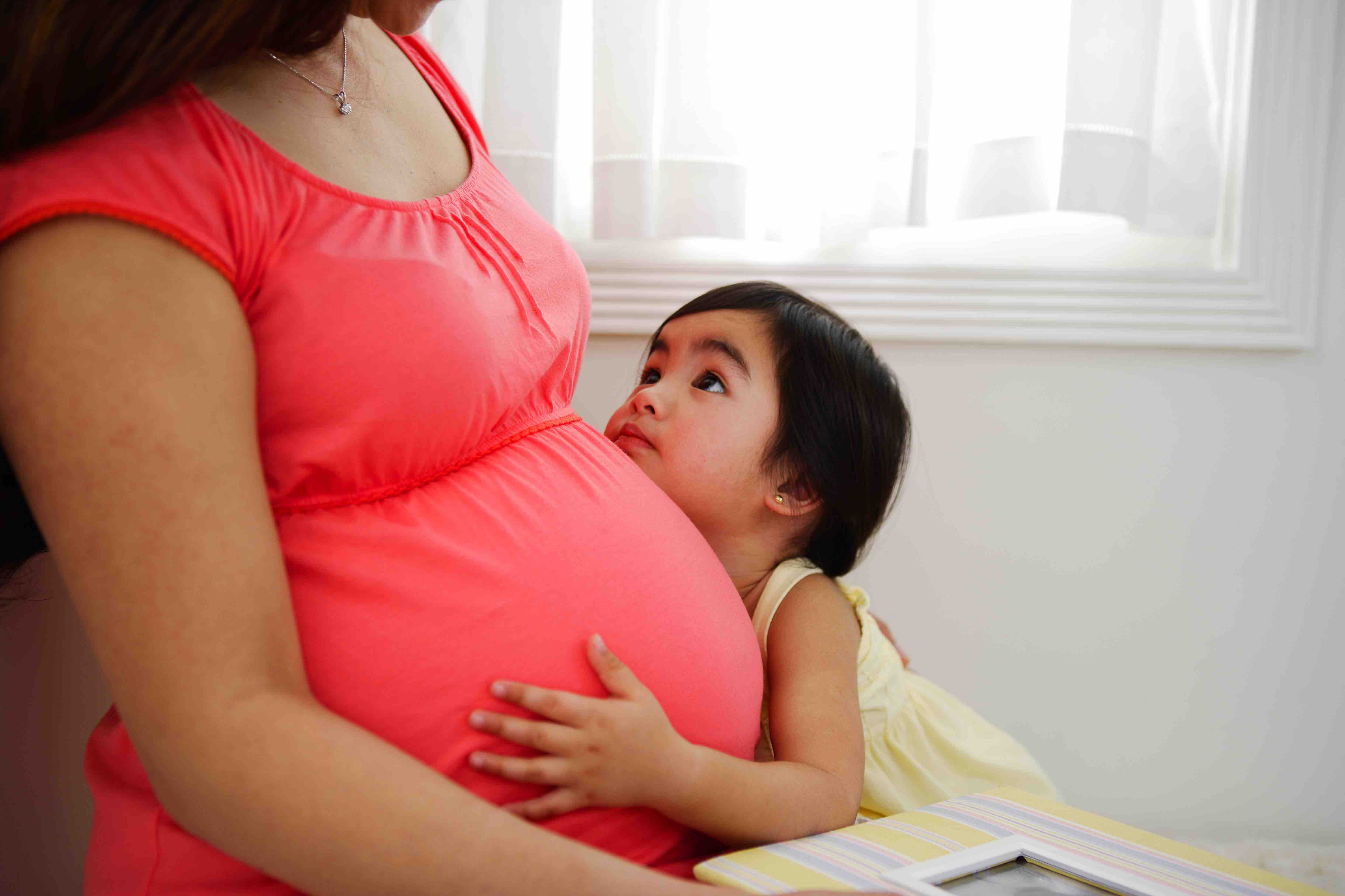 Infant looking up at mother in pink top.