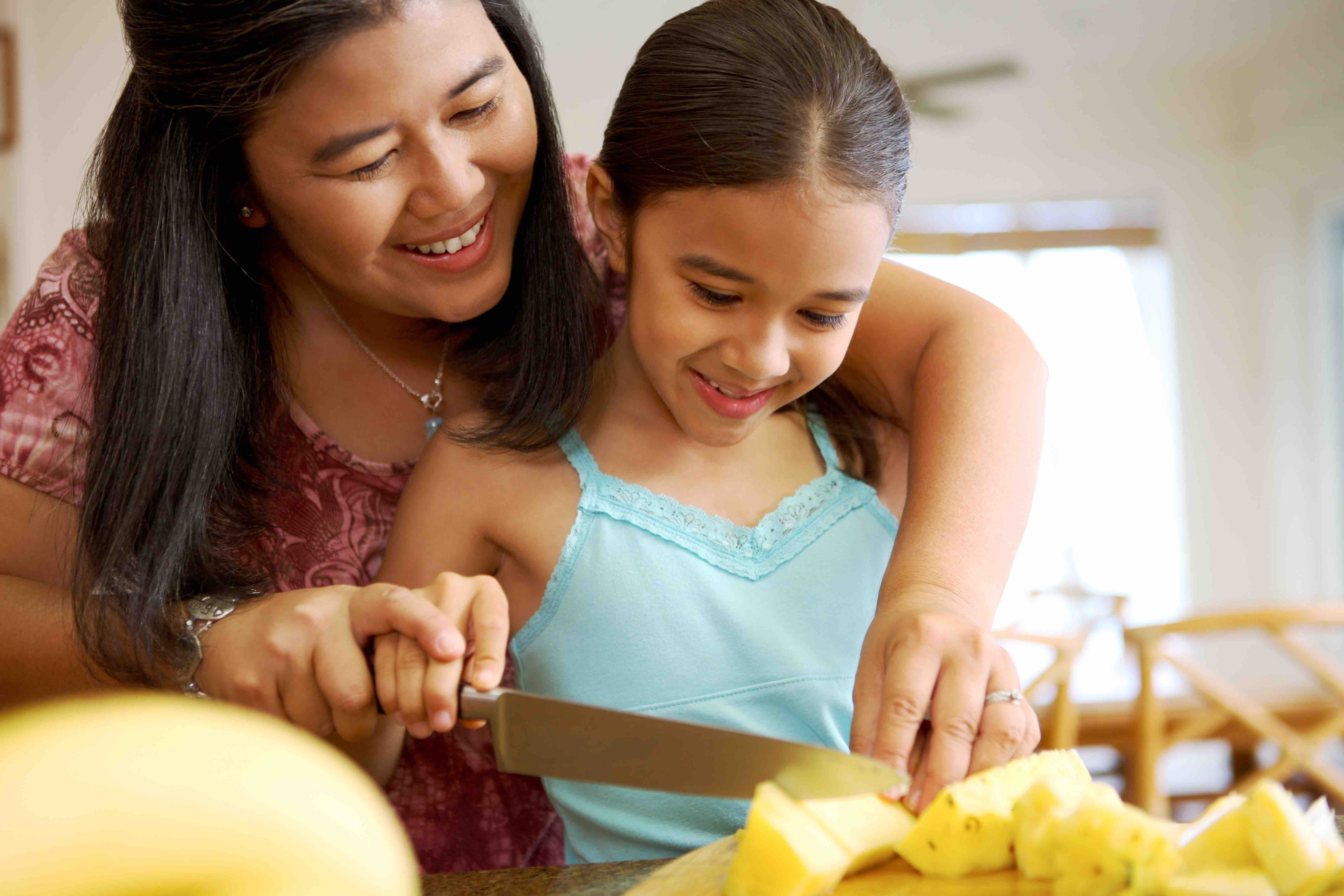 Mother and daughter cutting a pineapple.