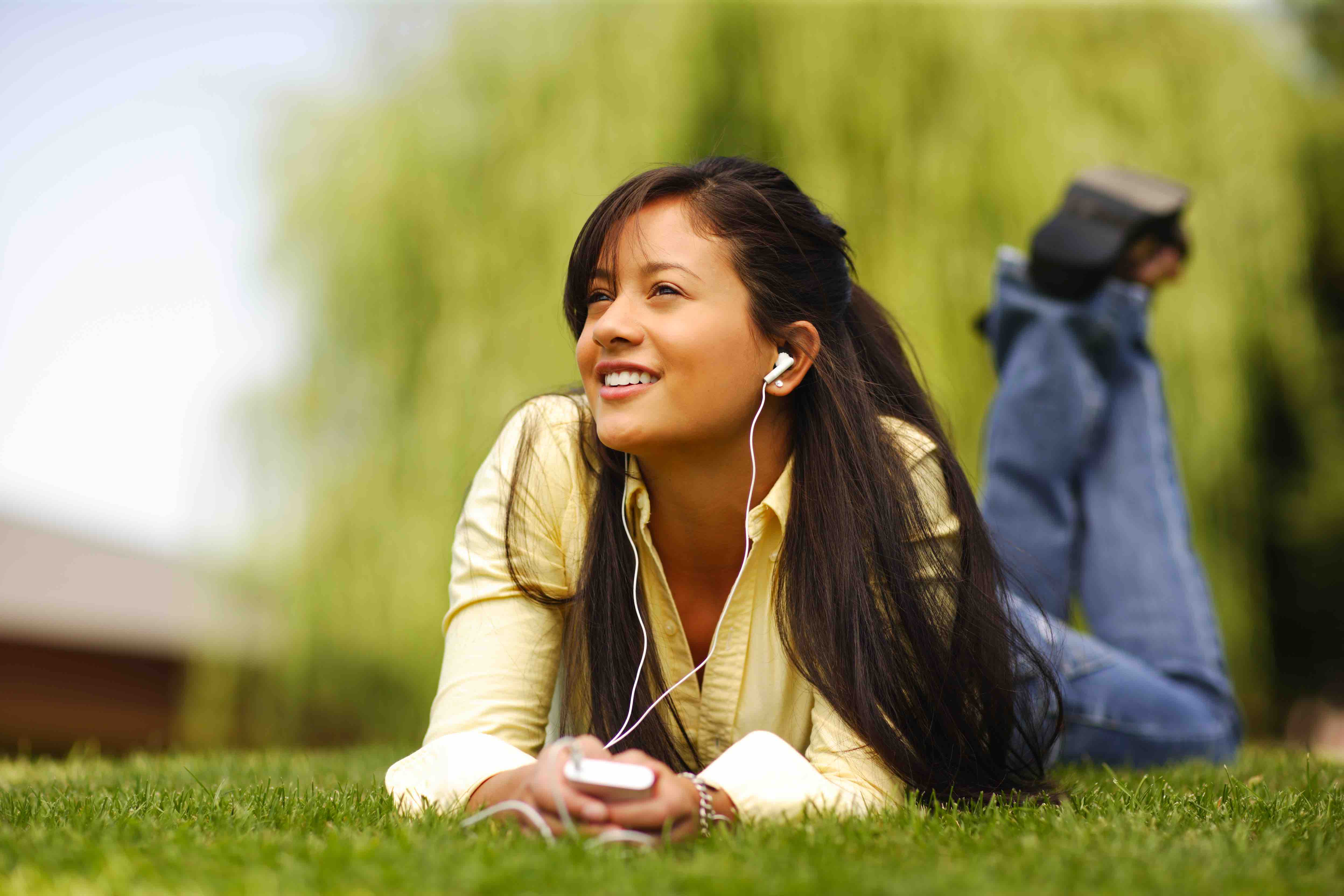 Woman listening to music while lying down on grass.